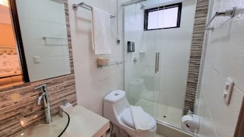 Un baño moderno con cabina de ducha de vidrio, inodoro y lavamanos con encimera de cristal.