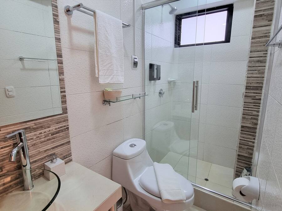 Un baño moderno con cabina de ducha de vidrio, inodoro y lavamanos con encimera de cristal.