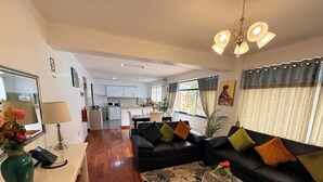 A modern living room with a sofa, a coffee table, and a dining area in the background. - Hotel Inkasabios Cusco (Cusco)