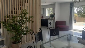Un salon moderne avec une table basse en verre, une plante en pot et un séparateur de pièce en bois.