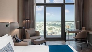 Ein modernes Hotelzimmer mit großem Fenster, einem Bett, einem Schreibtisch und einer Sitzecke.