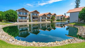 A resort with multiple buildings, a central pond, and surrounding greenery. - Our House Lake House by Beachside Mgt (Siesta Key)