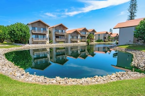 A resort with multiple buildings, a central pond, and surrounding greenery.