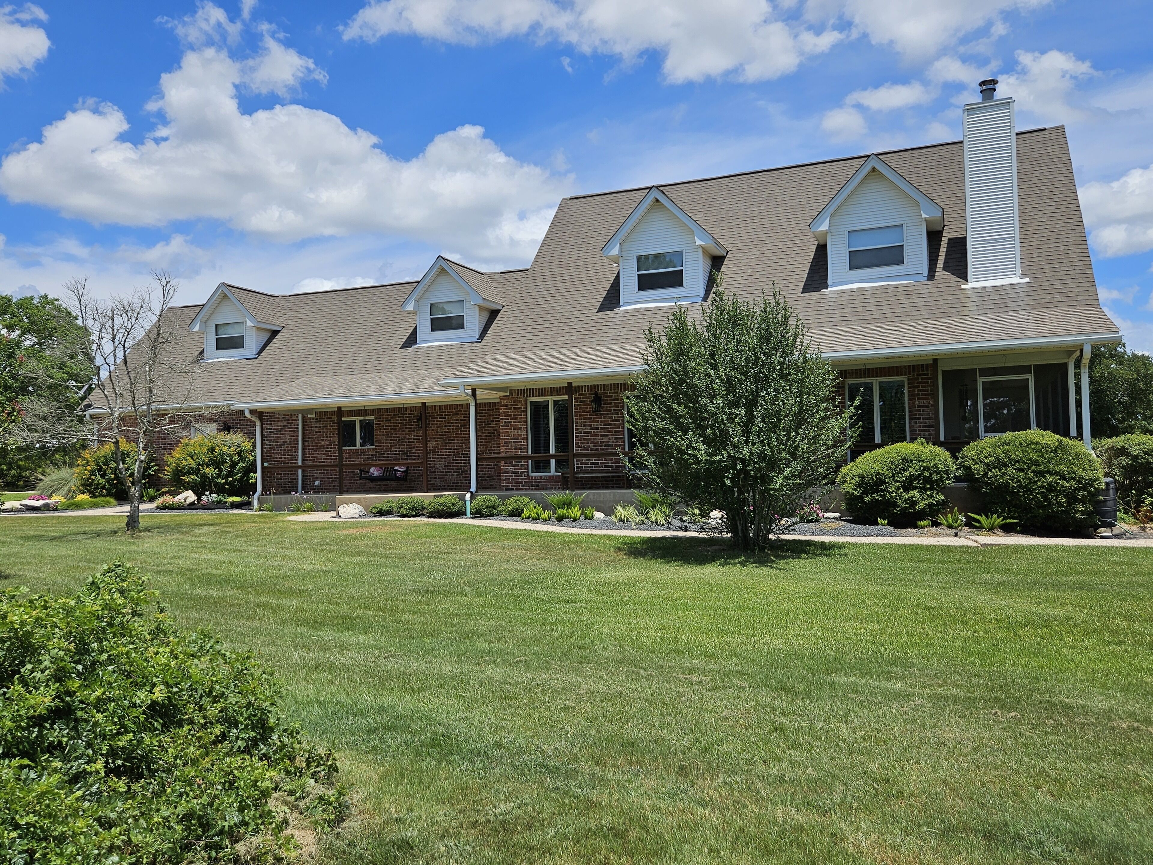 A two-story house with a covered porch, a chimney, and a well-maintained lawn.