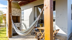 Un patio al aire libre con una hamaca, una mesa de madera y una chimenea de piedra.