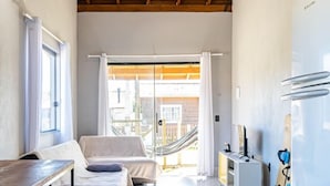 Una habitación amplia con techo de madera, una cama, un escritorio y un refrigerador.