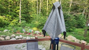 Terraza con una mesa de vidrio y dos sillas, rodeada por una barandilla de madera.