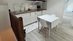 Een moderne keuken met dakraam, witte kasten en een eethoek met een witte tafel en stoelen.