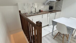 Een moderne keuken met een dakraam, witte kasten en een eethoek met een witte tafel en stoelen.