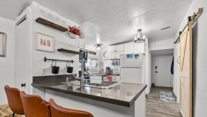 Una cucina moderna con isola centrale, mobili bianchi e una porta in legno.