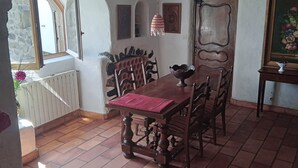 A dining area with a wooden table and chairs, a red table runner, and a hanging pendant light. - Calm and serenity, a feast for the eyes (Lachamp-Raphaël)