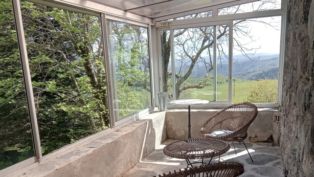 A sunroom with large windows, wicker chairs, and a stone floor. - Calm and serenity, a feast for the eyes (Lachamp-Raphaël)