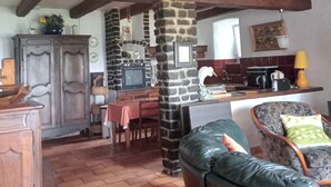 A rustic interior with exposed wooden beams, a stone fireplace, a dining area, and a leather sofa. - Calm and serenity, a feast for the eyes (Lachamp-Raphaël)