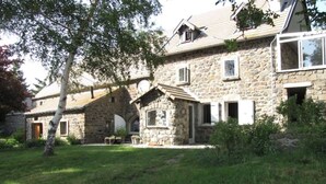 A stone house with a sloped roof, a small porch, and a grassy yard. - Calm and serenity, a feast for the eyes (Lachamp-Raphaël)