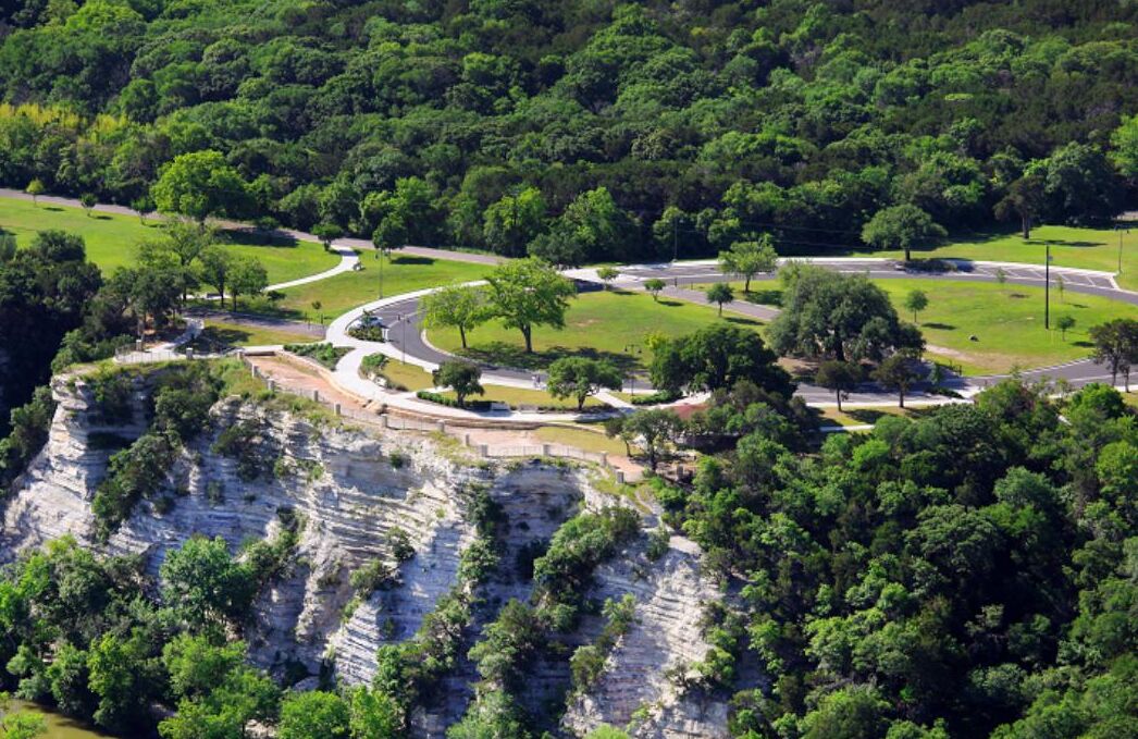 Vista aérea de un parque con caminos sinuosos, árboles y un acantilado.