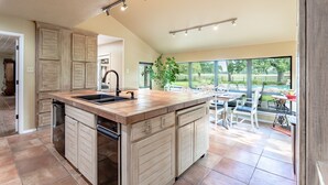A spacious kitchen with a large island, built-in appliances, and a view of the outdoor patio area. - Oak Tree Manor w/ Pool (Waco)
