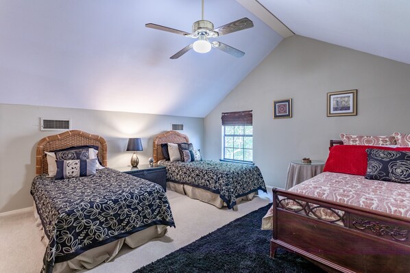A bedroom with two single beds, a ceiling fan, a window with blinds, and a small table with a lamp. - Oak Tree Manor w/ Pool (Waco)