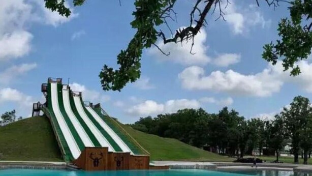 A water slide with a pool at the bottom. - Oak Tree Manor w/ Pool (Waco)
