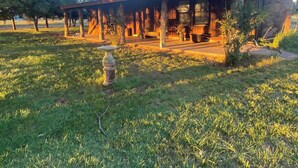 A rustic cabin with a stone exterior, a wooden porch, and a grassy yard. - Mountain Cabin ATV trails, convenient and comfort. Enjoy nature Lots of parking (Young)