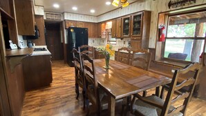 A spacious kitchen with wooden cabinets, a dining table with chairs, and a ceiling fan. - Mountain Cabin ATV trails, convenient and comfort. Enjoy nature Lots of parking (Young)