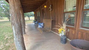 A covered porch with wooden beams, a concrete floor, and a rustic aesthetic. - Mountain Cabin ATV trails, convenient and comfort. Enjoy nature Lots of parking (Young)