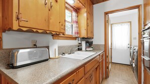 Cucina con mobili in legno, piano di lavoro in granito, un tostapane, un lavandino e una lavatrice.