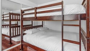 A bunk bed with white bedding in a room with wooden flooring and white walls. - The Rock House (Big Bear City)