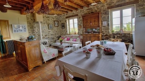 Una cocina rústica con paredes de piedra, vigas de madera y una mesa de comedor dispuesta para una comida.