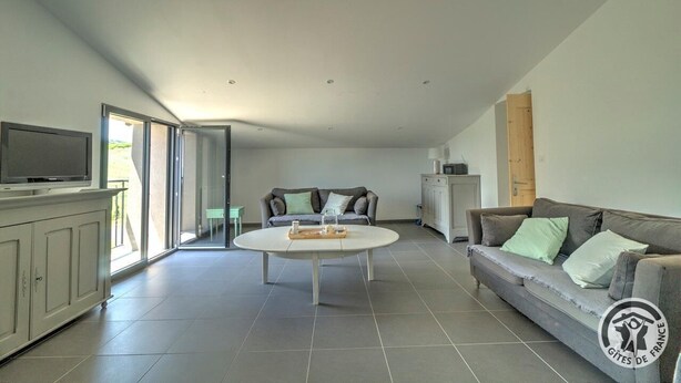 A spacious living area with a sofa, a coffee table, and a television on a cabinet.