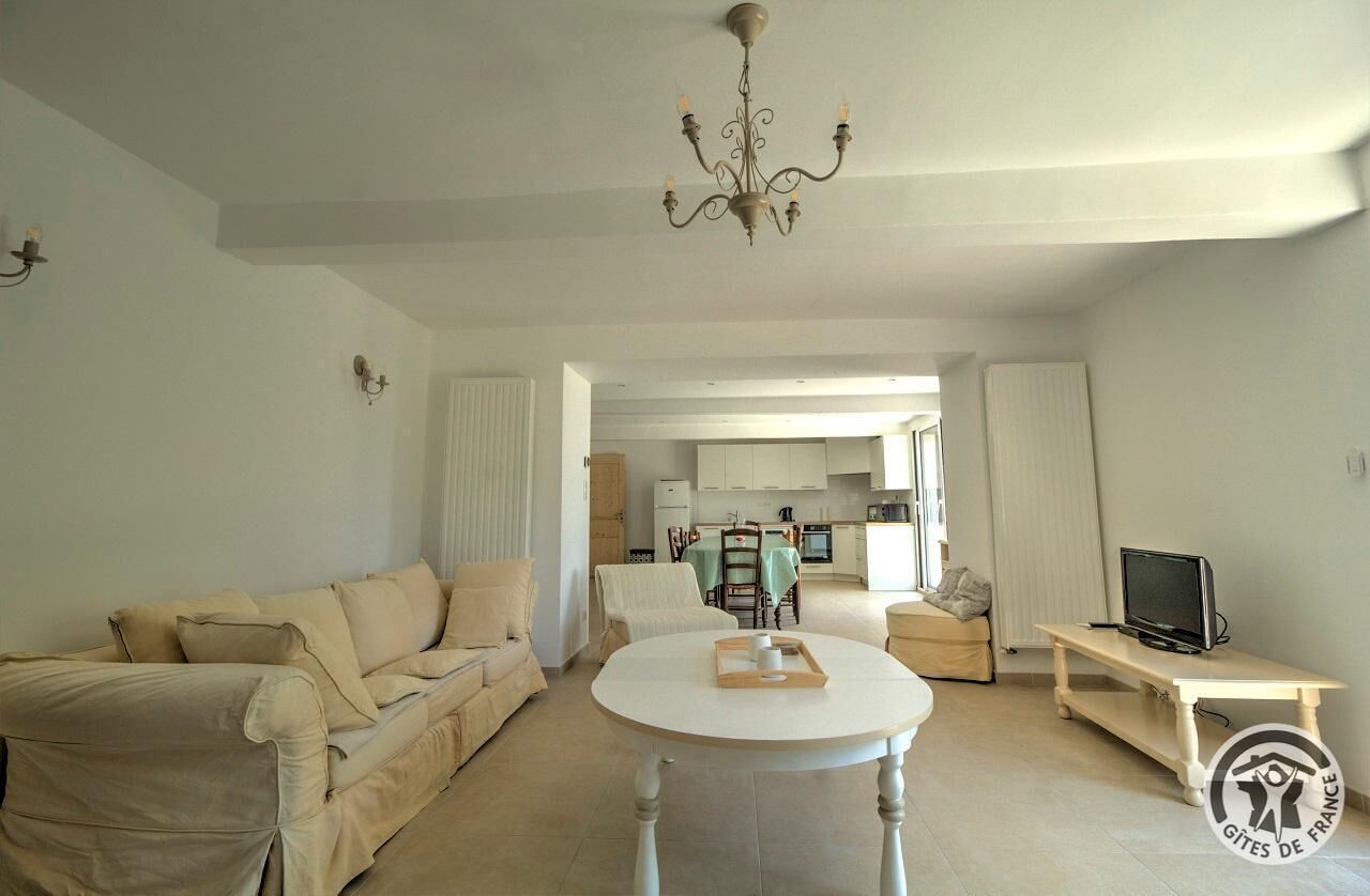 A spacious living room with a beige sofa, a round coffee table, and a television on a stand.