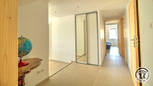 A hallway with a wooden floor, a globe on a wooden stand, and a sliding glass door leading to another room.