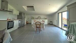 A spacious kitchen with modern appliances, a dining area with a table and chairs, and a balcony with a view.