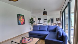 Una sala de estar moderna con un sofá seccional azul, una mesa de centro y una obra de arte colorida en la pared.
