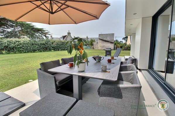 An outdoor patio with a table, chairs, and an umbrella.