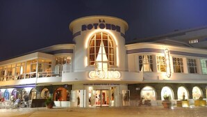 A casino building with a prominent arched entrance and illuminated signage. - Villa des Dîmes - Pleneuf VAL Andre (PLENEUF VAL ANDRE)