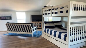 A room with a bunk bed, a sofa, a TV, and a game room sign. - Gorgeous, Secluded Hill Country Escape Near River + Game room! (Llano)