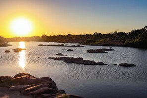 A river with rocks and a sunset in the background. - Gorgeous, Secluded Hill Country Escape Near River + Game room! (Llano)