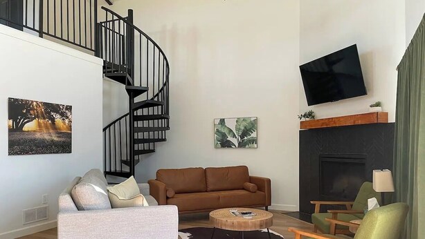 A modern living room with a sofa, armchairs, a coffee table, and a fireplace. - Gorgeous, Secluded Hill Country Escape Near River + Game room! (Llano)