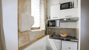 Uma cozinha compacta com micro-ondas, pia e pequeno frigorífico.