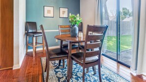 A dining area with a round table, four chairs, a vase with a plant, and two framed pictures on the wall. - Escape to Olivia's Hideaway in Allen! Close  to shopping,Eat, and entertainment (Allen)