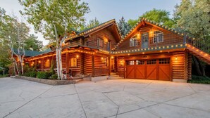 A large log cabin with a spacious driveway and a well-lit front porch. - The Moose & Bear Cabin at Timpanogos (Highland)