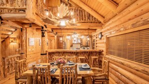A log cabin interior with a dining area featuring a wooden table and chairs, a kitchen area, and a ceiling with a natural light fixture. - The Moose & Bear Cabin at Timpanogos (Highland)