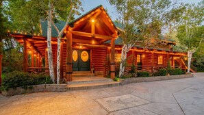 A log cabin with a porch, a green door, and a stone pathway leading to the entrance. - The Moose & Bear Cabin at Timpanogos (Highland)