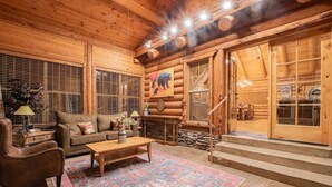 A log cabin interior with a sofa, coffee table, and rug. - The Moose & Bear Cabin at Timpanogos (Highland)