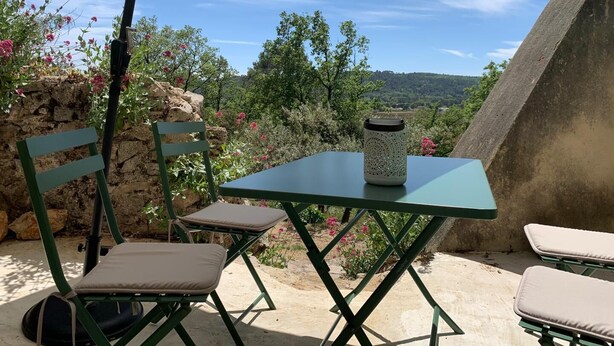 An outdoor seating area with a table and chairs under a canopy, overlooking a scenic landscape.