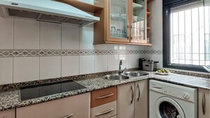 A kitchen with a built-in oven, a sink, and a washing machine.