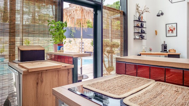 Una cocina moderna con encimeras de madera, estufa integrada y un amplio ventanal con vistas a un jardín.