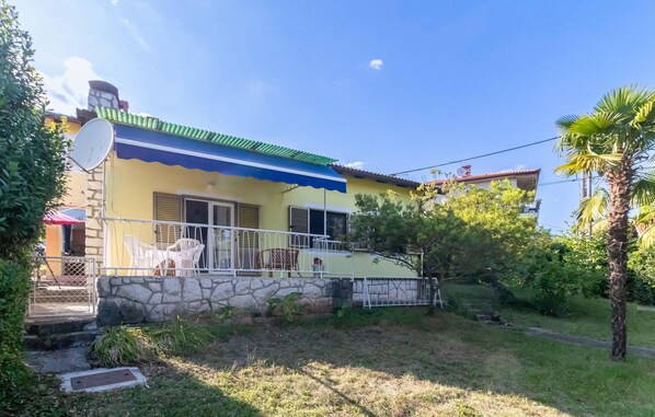 Ein zweistöckiges Haus mit Balkon, Satellitenschüssel und Steinmauer.