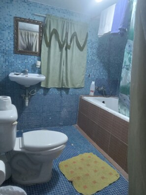 A bathroom with a toilet, sink, bathtub, and a mirror.