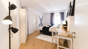 A modern bedroom with a bed, bedside table, lamp, and a wall-mounted artwork. - APPARTIO - Modern country-style vacation apartment for 6 people (Ölbronn-Dürrn)